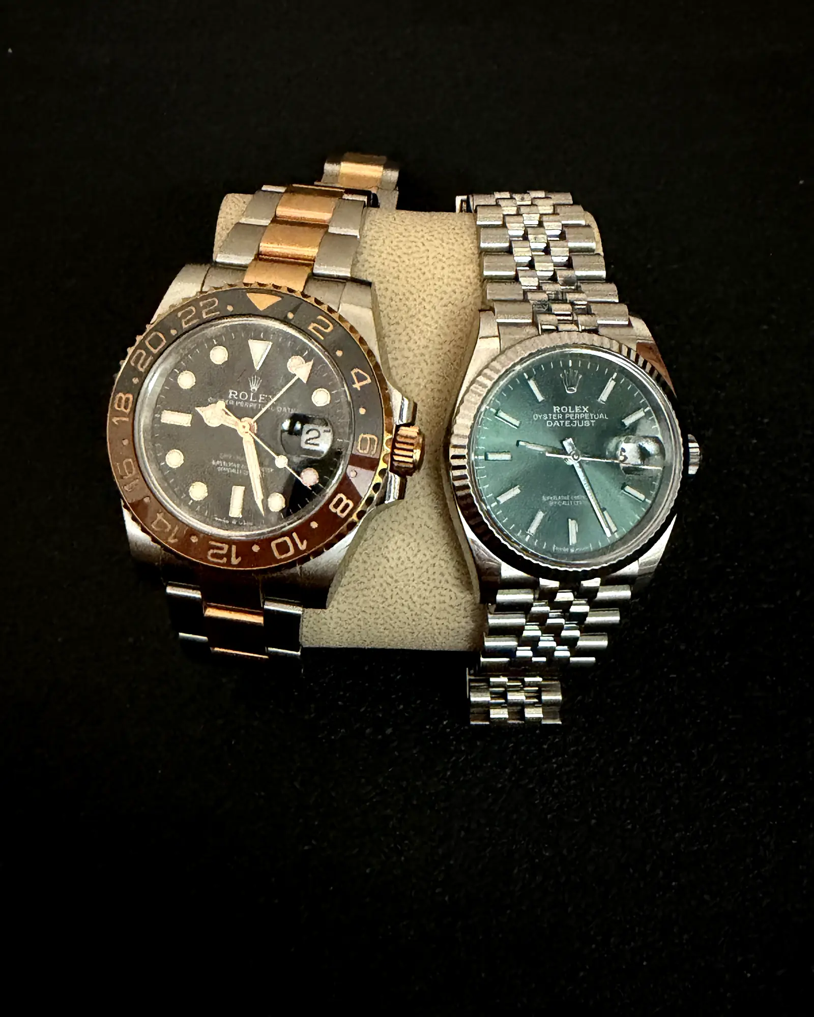 Two luxury wristwatches resting on a leather pillow against a dark background